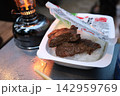 キャンプ場でランタンの傍にある食事トレーとステーキ肉料理 142959769