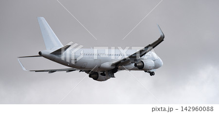 The plane is taking off, passenger airliner. A white plane flies in storm clouds. Retracting the landing gear The plane is taking off, passenger airliner. A white plane flies in storm clouds. Retracting the landing gear 142960088