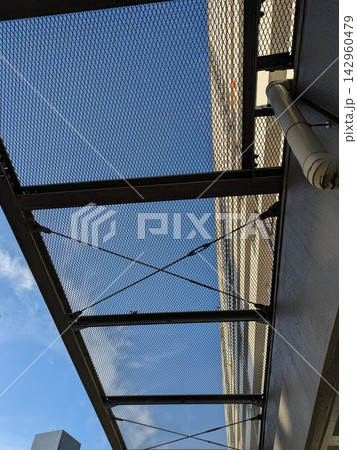 建物に設置された金属製の落下防止メッシュと青空 142960479