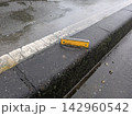 雨に濡れた道路の縁石に設置された黄色い反射板 142960542