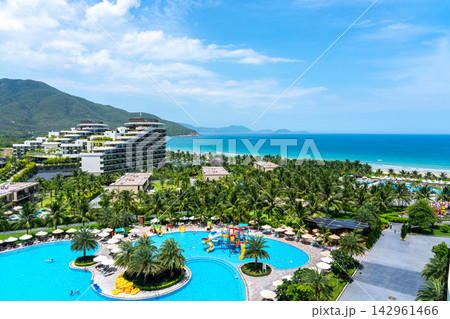 A Stunning View of a Tropical Resort with Lush Palm Trees and a Sparkling Blue Pool Overlooking the Tranquil Ocean A Stunning View of a Tropical Resort with Lush Palm Trees and a Sparkling Blue Pool Overlooking the Tranquil Ocean 142961466