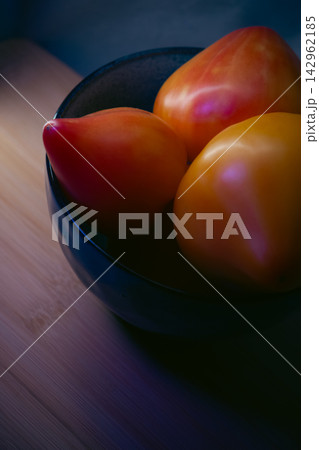 Fresh ripe oxheart tomatoes in a ceramic bowl on wooden board 142962185