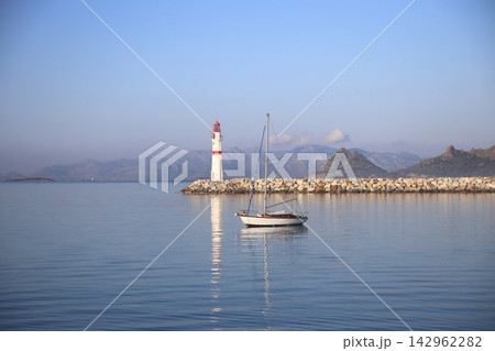 Seascape at sunshine. Lighthouse and sailings on the coast. Seaside town of Turgutreis and spectacular sunshine Seascape at sunshine. Lighthouse and sailings on the coast. Seaside town of Turgutreis and spectacular sunshine 142962282