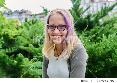 Smiling teenage girl wearing glasses looking at camera outdoors portrait Smiling teenage girl wearing glasses looking at camera outdoors portrait 142963140