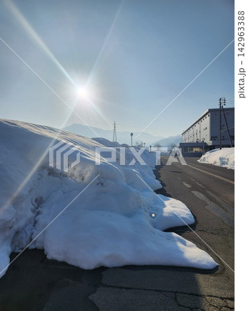 青空とまぶしい日差しに映える、道路沿いの巨大な雪の壁。日本の冬の風景 青空とまぶしい日差しに映える、道路沿いの巨大な雪の壁。日本の冬の風景 142963388