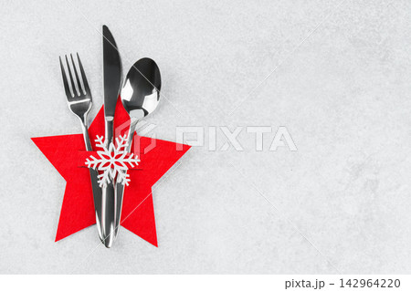 Christmas table setting with silver cutlery in red star shaped cutlery holder, background copy space 142964220