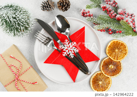 Festive Christmas table setting, dinnerware. White plate and cutlery in red star shaped holder 142964222