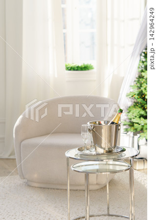 Champagne bottle in ice bucket with glasses on glowing Christmas tree lights background Champagne bottle in ice bucket with glasses on glowing Christmas tree lights background 142964249