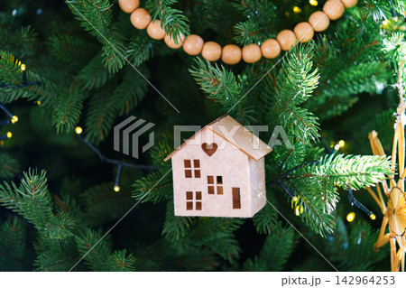 Handmade craft holiday Christmas ornaments on festive green spruce tree, natural wooden rustic decor 142964253
