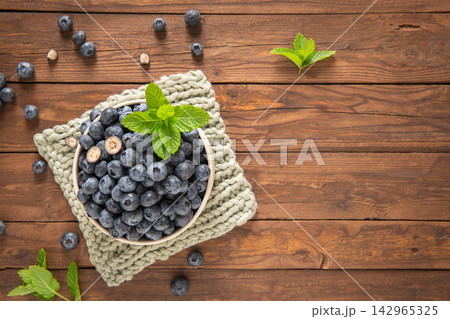 Fresh blueberries bowl with mint on wooden table Fresh blueberries bowl with mint on wooden table 142965325