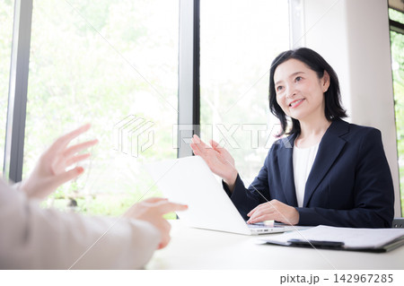 笑顔で説明する50代の日本人女性ビジネス、住宅のローン金利見直しファイナンシャルプランナーイメージ 142967285