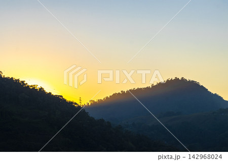 Golden colorful sunrise behind the tropical mountain mountains in Brazil. Golden colorful sunrise behind the tropical mountain mountains in Brazil. 142968024