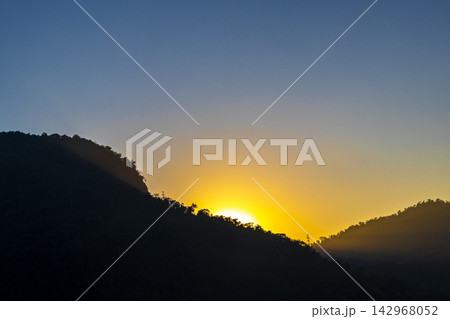Golden colorful sunrise behind the tropical mountain mountains in Brazil. Golden colorful sunrise behind the tropical mountain mountains in Brazil. 142968052