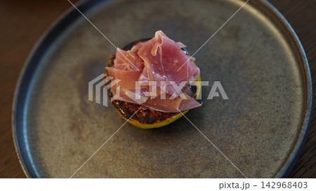 シックな平皿に盛られた焼きいちじくと生ハムの絶品オードブル 142968403