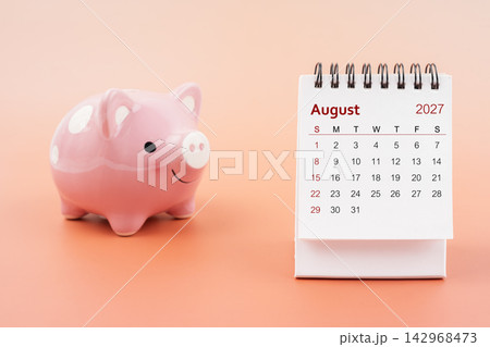 Desk calendar for August 2027 and pink piggy bank. Desk calendar for August 2027 and pink piggy bank. 142968473
