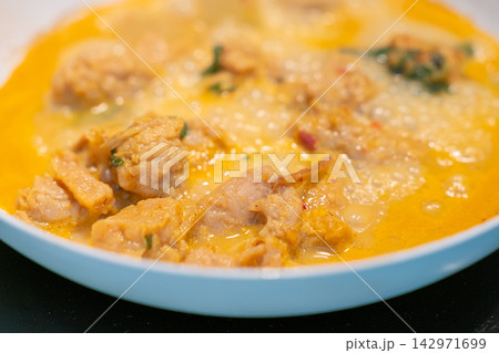 Creamy chicken curry stew in blue bowl with herbs and spices 142971699