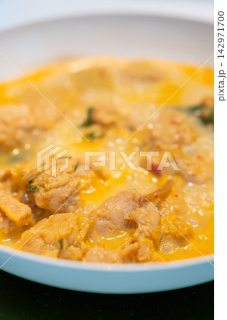 Creamy chicken curry in white bowl with golden sauce and herbs 142971700