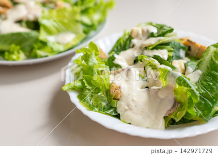 Creamy romaine salad with grilled chicken and dressing served on white plate Creamy romaine salad with grilled chicken and dressing served on white plate 142971729