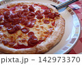 とろけるチーズとソーセージがのった出来立てのピザ とろけるチーズとソーセージがのった出来立てのピザ 142973370
