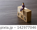 Businesswoman figurine sitting on wooden faq blocks 142977046