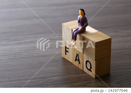 Businesswoman figurine sitting on wooden faq blocks Businesswoman figurine sitting on wooden faq blocks 142977046
