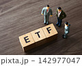 Business figurines discussing etf investment strategy on wooden table 142977047