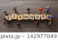 Business figurines collaborating around wooden teamwork blocks 142977049