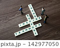 Miniature figures interacting with crossword puzzle words leadership, inspire, support, teamwork 142977050