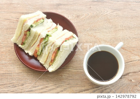 slice sandwich stuffed ham cheese with vegetable salad on plate and black coffee cup  142978792