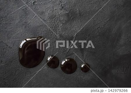 Top view of dark sauce drops on a black textured background 142979266