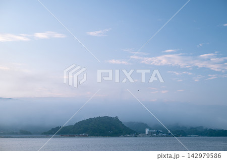 6月の日の出前に沿岸を包む幻想的な朝靄と広大な朝空が広がる海辺の風景 6月の日の出前に沿岸を包む幻想的な朝靄と広大な朝空が広がる海辺の風景 142979586