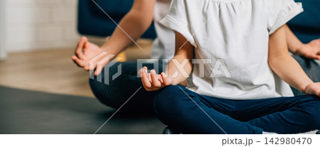A mother and her daughter find serenity in family yoga sitting in lotus position 142980470