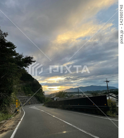 夕焼け空の下を続く山あいの道路 夕焼け空の下を続く山あいの道路 142980748