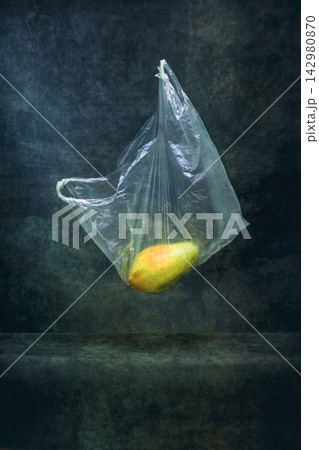 Ripe pear in a cellophane bag on a string on a dark background 142980870