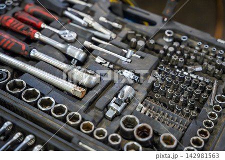 Mechanic tool set with ratchets sockets bits and wrenches in auto repair shop. Professional equipment represents car maintenance and vehicle repair service Mechanic tool set with ratchets sockets bits and wrenches in auto repair shop. Professional equipment represents car maintenance and vehicle repair service 142981563