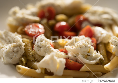 Penne pasta with mozzarella, pesto and fresh cherry tomatoes Penne pasta with mozzarella, pesto and fresh cherry tomatoes 142982088