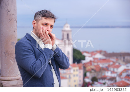 Man plays harmonica outdoors in city street Man plays harmonica outdoors in city street 142983285