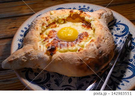 Adjarian Khachapuri Georgian boat shaped cheese bread topped with a raw egg yolk and butter Adjarian Khachapuri Georgian boat shaped cheese bread topped with a raw egg yolk and butter 142983551