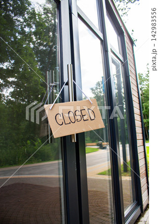 CLOSED sign hanging on small shop door. Small business shutting down due to financial crisis. Local business unable to survive economic pressure 142983556