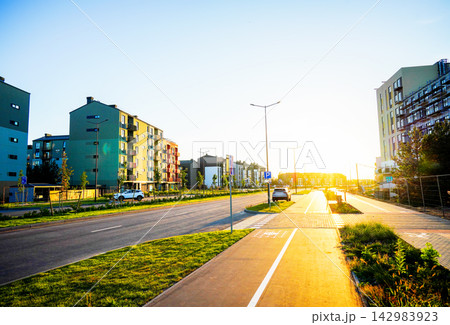 Sunrise lighting up city street with condominium complex buildings and parked cars 142983923