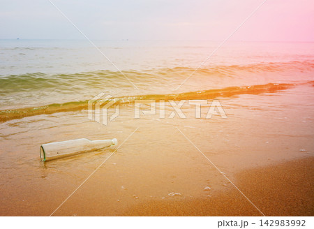Message in bottle on sandy beach near ocean with gentle waves rolling 142983992