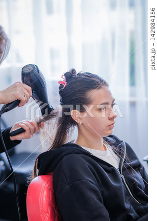 Keratin hair straightening process in beauty salon with hair stylist drying hair. 142984186