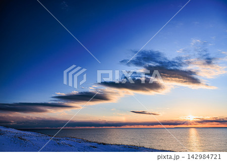 北海道道東の極東絶景 地平線に沈む夕日と雪覆う落石海岸三里浜の海岸美 北海道道東の極東絶景 地平線に沈む夕日と雪覆う落石海岸三里浜の海岸美 142984721