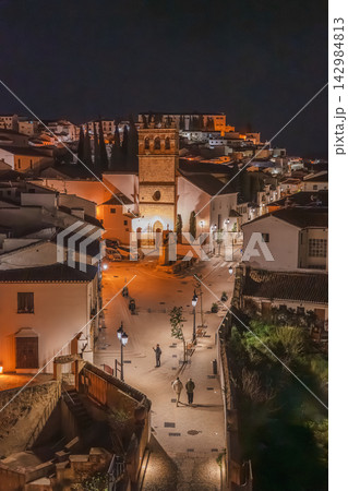 Illuminated bell tower and plaza overlooking a hillside white village at night Illuminated bell tower and plaza overlooking a hillside white village at night 142984813
