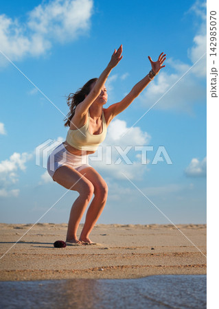 Utkatasana Chair Pose Yoga on Beach Under Blue Sky 142985070
