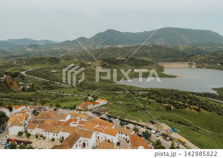 Elevated view of village rooftops overlooking a reservoir and green hills 142985822