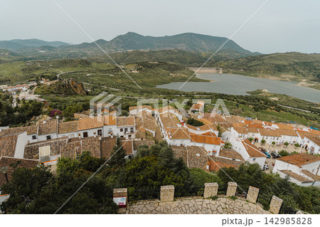Elevated view of village rooftops overlooking a reservoir and green hills 142985828