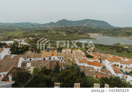 Elevated view of village rooftops overlooking a reservoir and green hills 142985829