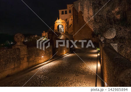 Illuminated archway leads toward Ronda's clifftop fortress at night Illuminated archway leads toward Ronda's clifftop fortress at night 142985894