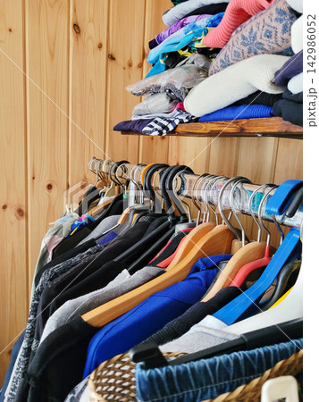 Wooden shelf with folded clothes and hangers in wardrobe 142986052